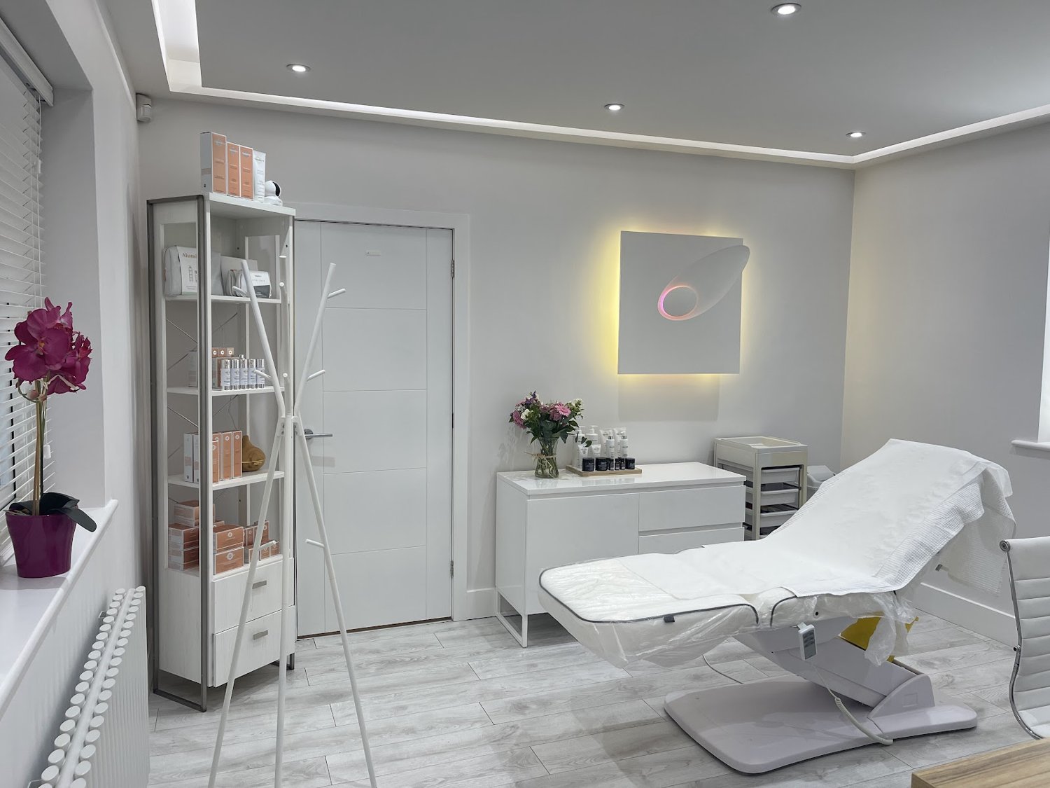 A calm, light treatment room at the iSkincare clinic with a signature halo wall light.